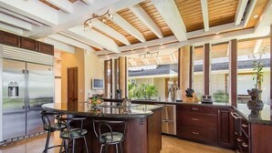 Una cocina moderna con una isla central, taburetes de bar y un refrigerador grande.