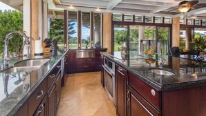 Una cocina moderna con una isla grande, electrodomésticos de acero inoxidable y vistas al exterior.