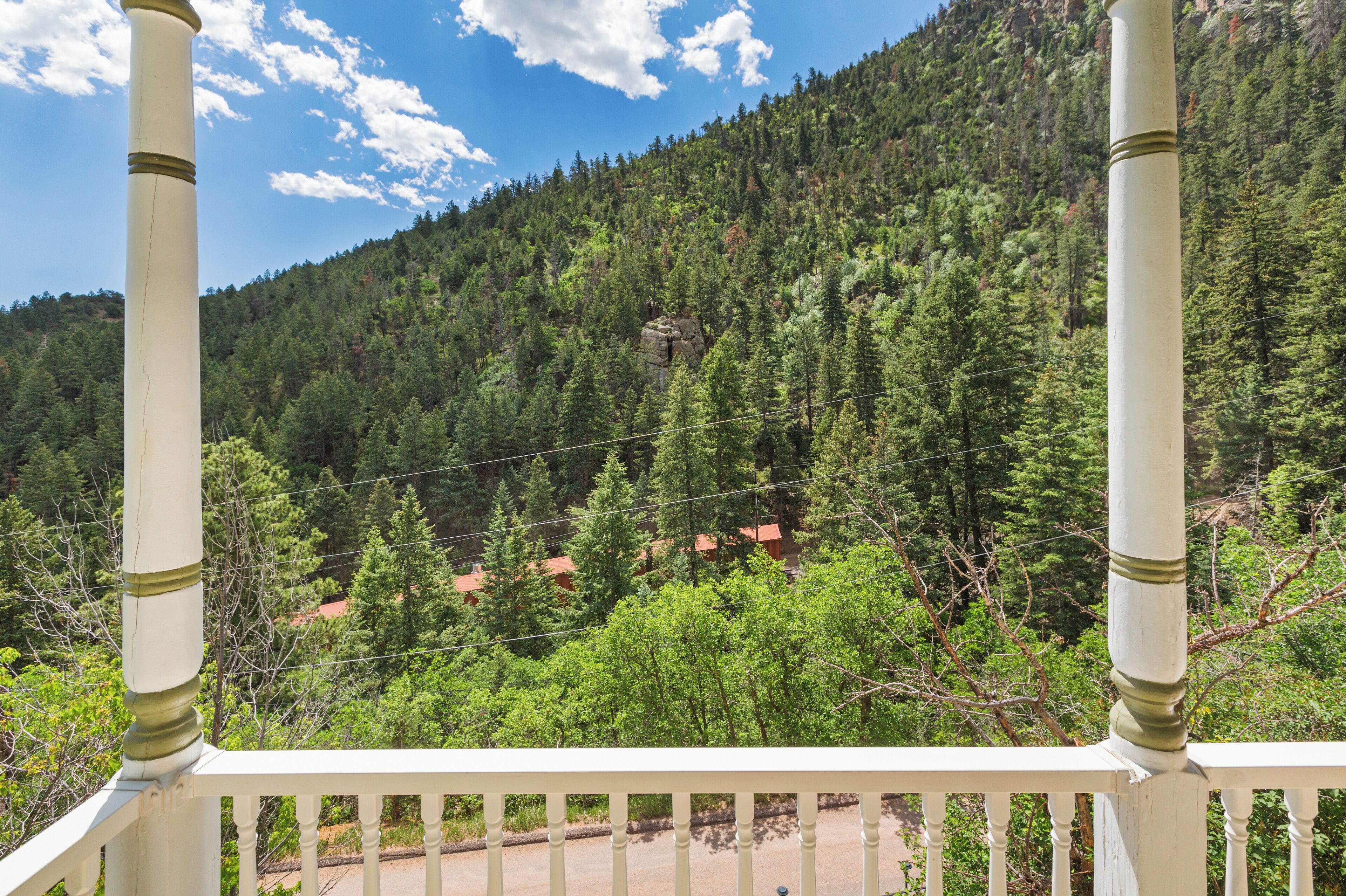 A balcony with white balustrades overlooking a forested mountain area.