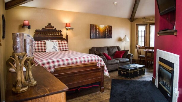 Ein gemütliches Schlafzimmer mit einem Holzbett, einem Ledersofa, einem Kamin und einem Essbereich.