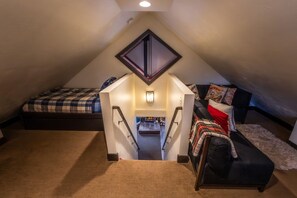 A loft bedroom with a sloped ceiling, a bed, a sofa, and a small kitchen area. - Private mountain escape • Above the creek • Hot tub • Quiet setting • Tucked into Sundance Canyon (Sundance)