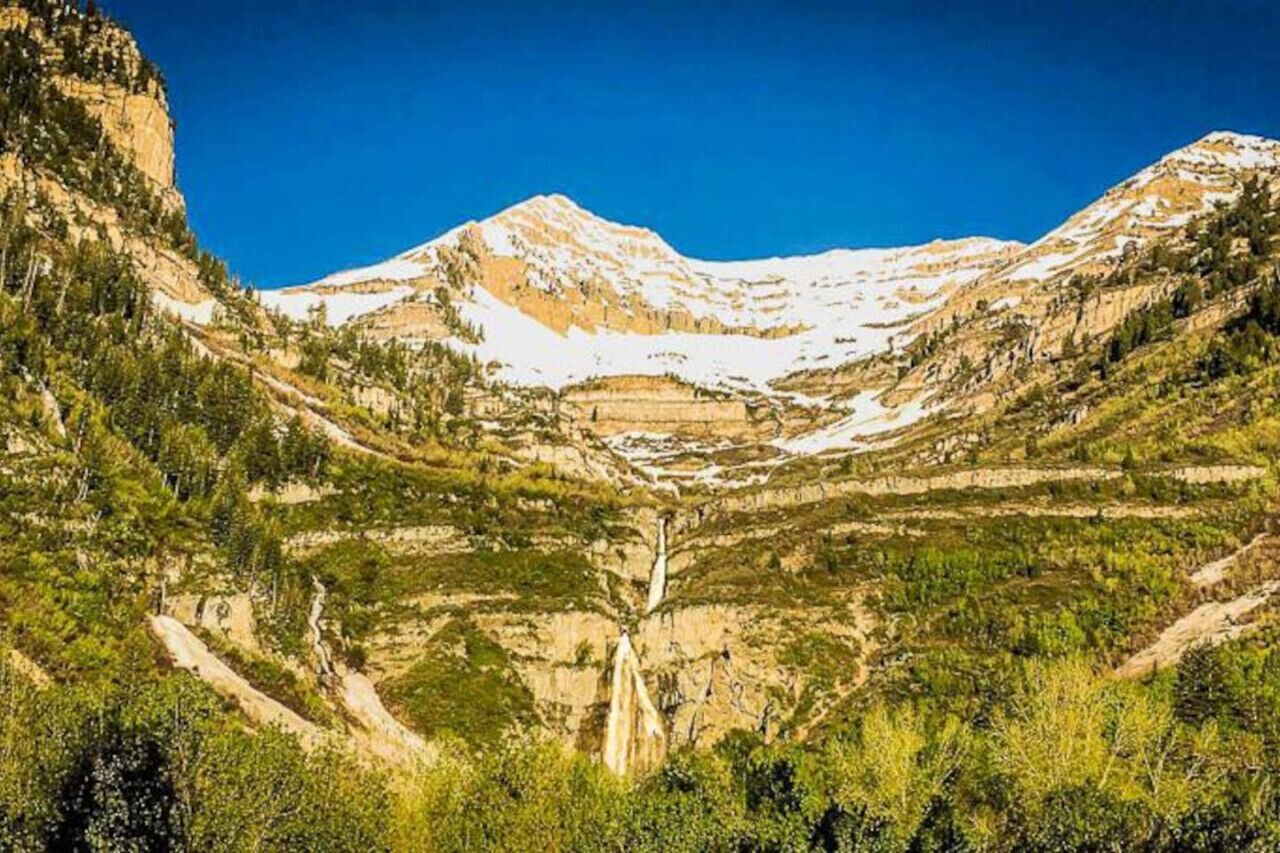 A mountainous landscape with a waterfall, terraced fields, and dense vegetation.