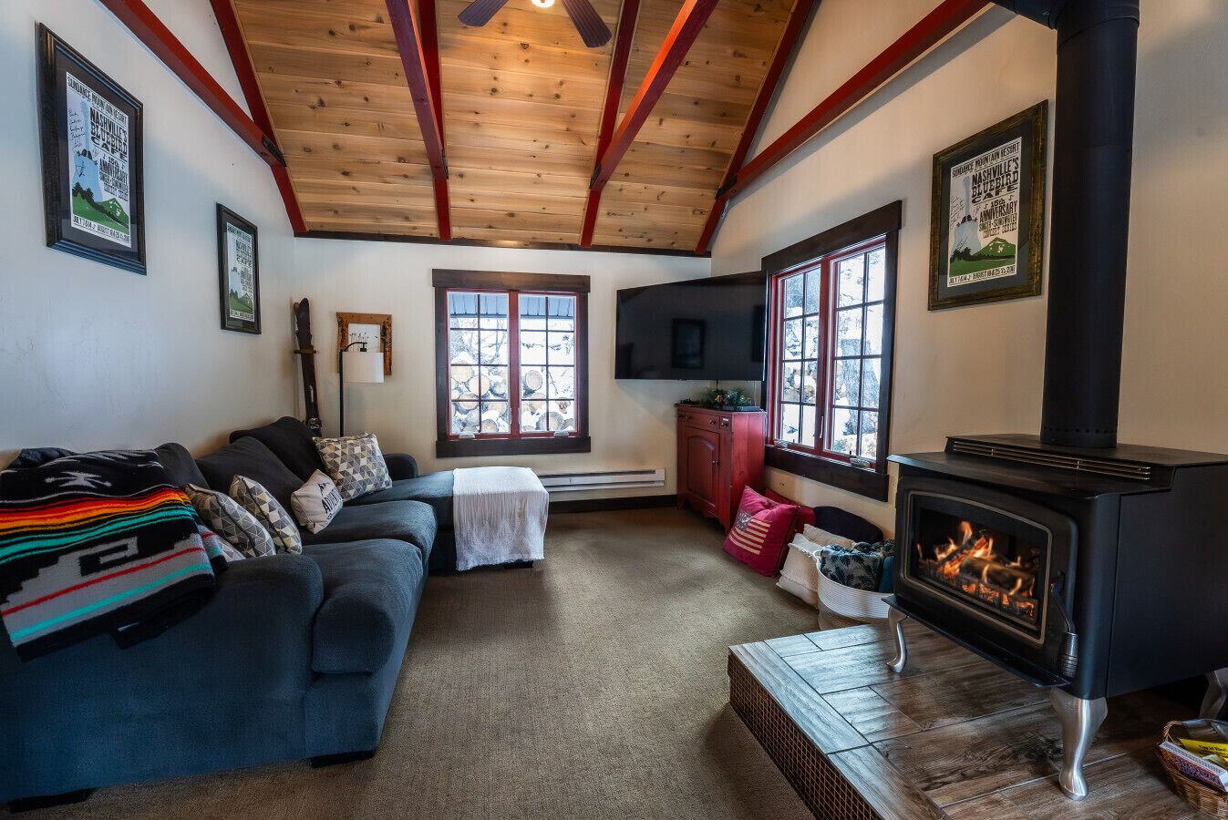 A cozy living room with a fireplace, a sofa, a TV, and a window with a view.