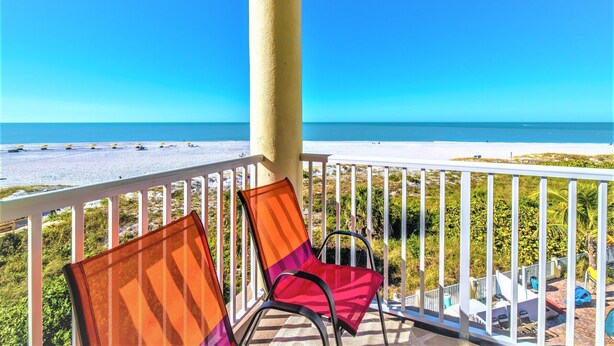 Een balkon met twee stoelen met uitzicht op een strand.