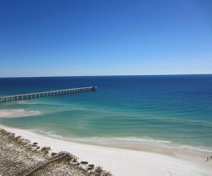 A beach with a long pier extending into the ocean.