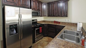 A kitchen with dark wood cabinets, stainless steel appliances, granite countertops, and a double sink. - 6A4 Views from Patio, Two Car Garage, Community Pool & Hot Tub (Moab)