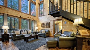 A spacious living room with leather sofas, a coffee table, and a staircase leading to an upper level. - 4 Bedroom 3.5 Bath-Pickleball/Basketball Court, Game Room, Hot Tub & Playground (Broken Bow)