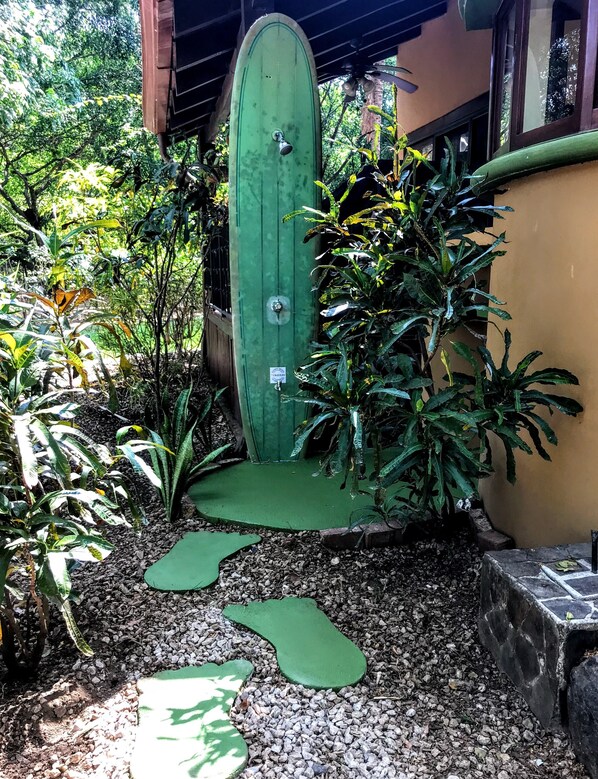 A green door with a keyhole, surrounded by tropical plants and a gravel path.