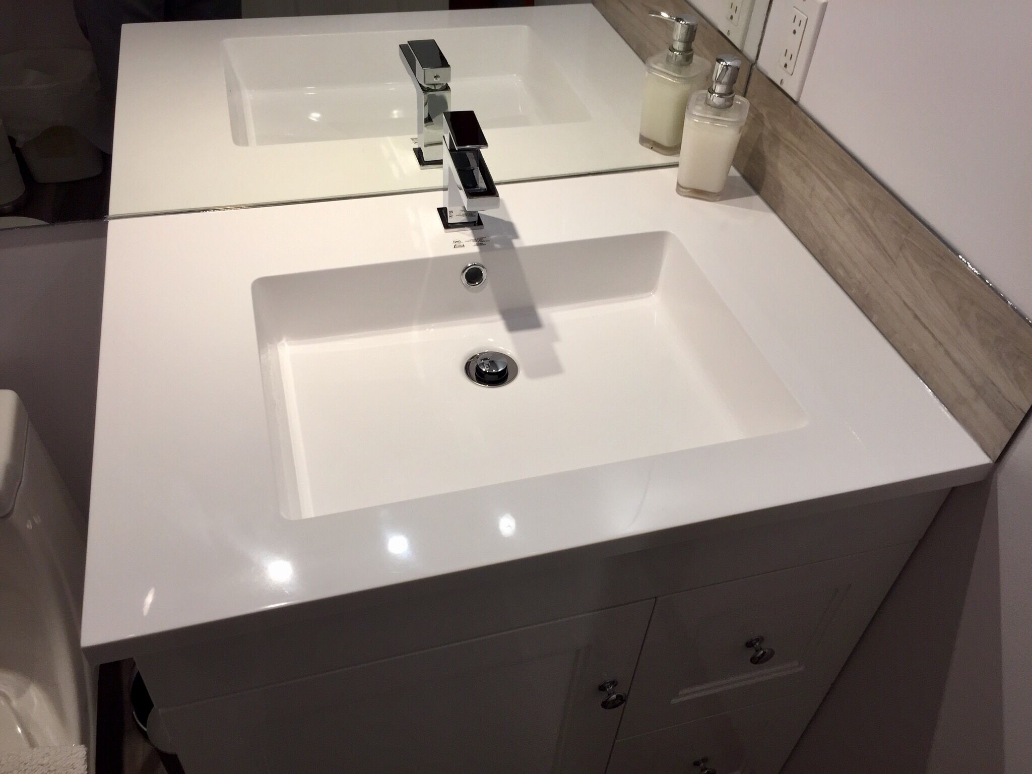 A bathroom with a white sink, a mirror above it, and two soap dispensers.