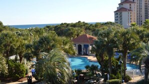 Ein Resort mit Swimmingpool, umgeben von Palmen und Blick auf den Ozean.