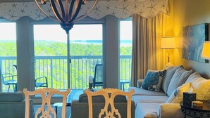 Ein Zimmer mit Balkon, einer Couch, einem Fernseher und einem Tisch.