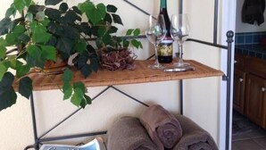 A wicker shelf with a bottle of wine, glasses, and a plant. - Private Room with Attached Sun Room and Covered Deck (Aptos)