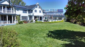 A large, two-story house with a well-maintained lawn, a covered porch, and solar panels on the roof. - Private Room with Attached Sun Room and Covered Deck (Aptos)