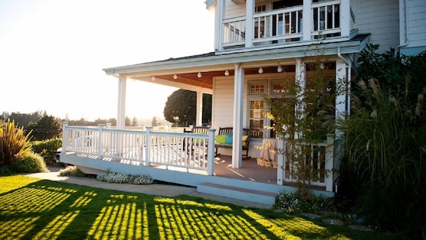 A two-story house with a covered porch, a balcony, and a well-maintained lawn. - Private Room with Attached Sun Room and Covered Deck (Aptos)