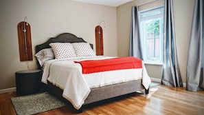 A neatly arranged bedroom with a bed, bedside lamps, a window with curtains, and a wooden floor. - Hiking, Biking, Golfing, Paddle Boarding, Kayaking and MORE! (Kent)