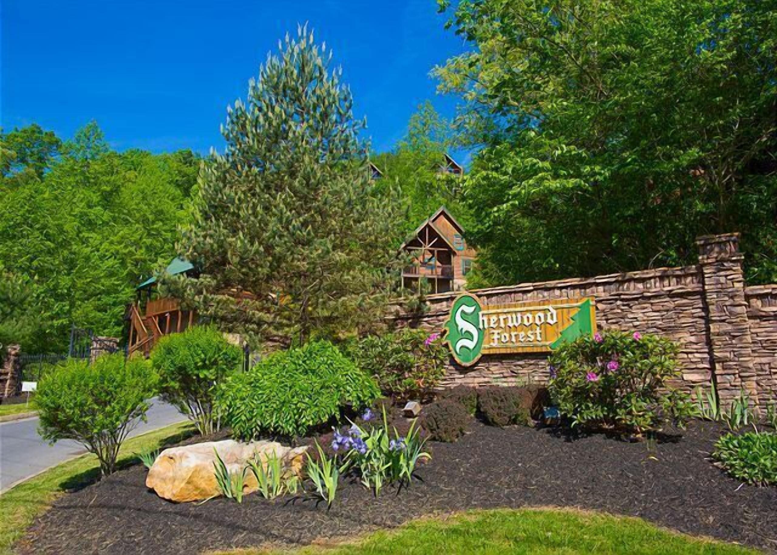 A sign for Sherwood Forest with a rustic stone wall and a wooden cabin structure.