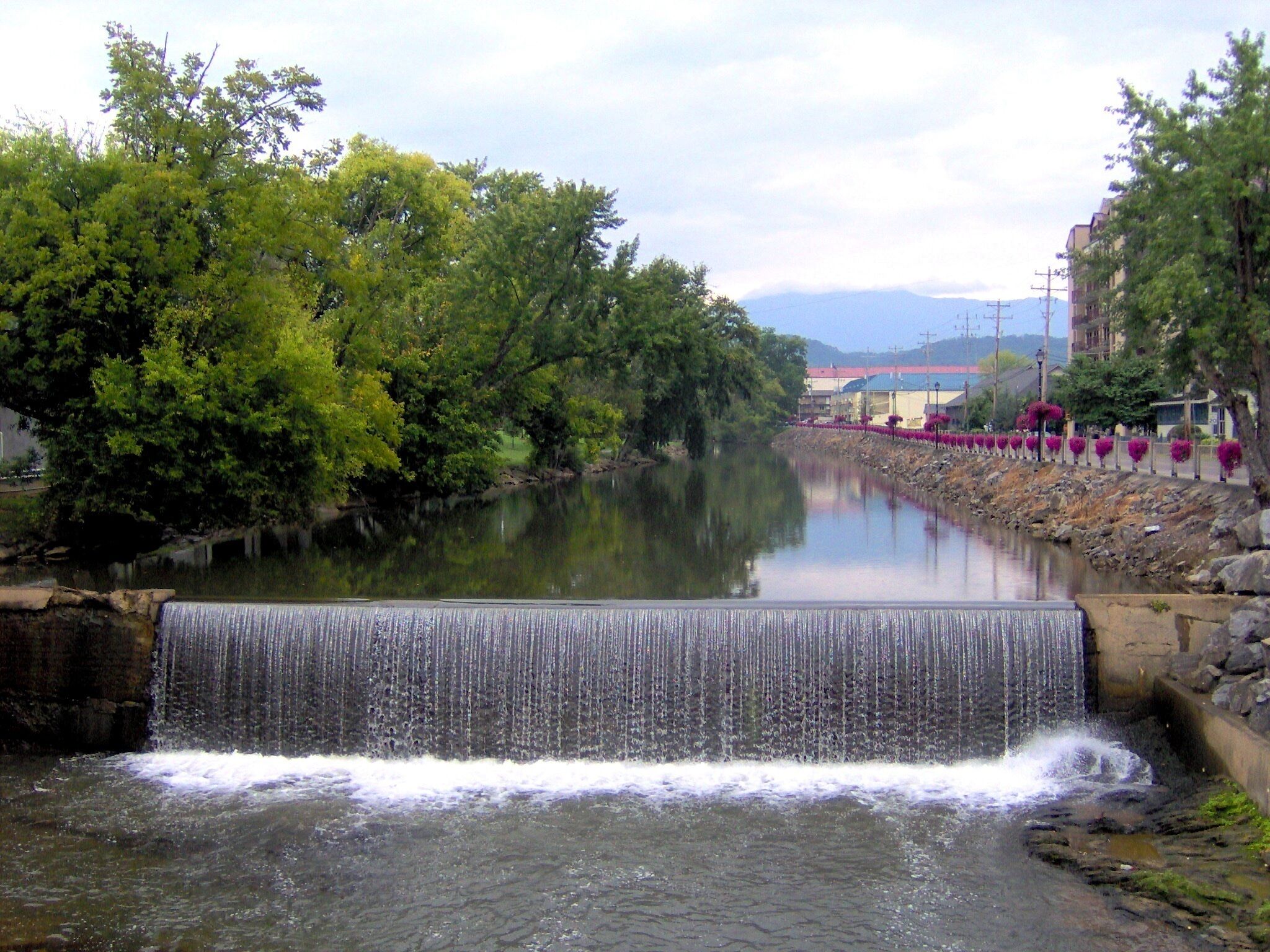 A waterfall in a natural setting with trees and a river.