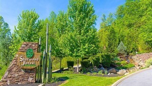 A sign for Sherwood Forest with a stone base and a green emblem, surrounded by lush greenery and trees. - 5 miles to Gatlinburg, Hot Tub, Views, 4 BEDROMS: JEEP INVASION, ROD RUN, SPARKS (Pigeon Forge)
