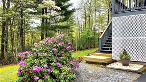 Une propriété résidentielle dotée d’un jardin bien entretenu, d’un escalier menant à un porche et d’une clôture blanche.
