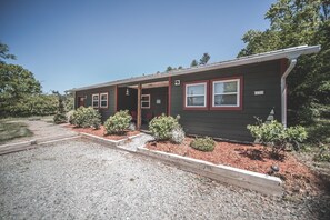 A single-story building with a dark exterior and red trim, featuring a front door and two windows. - Pisgah Adventure Cabin. Biking and hiking dream! (Pisgah Forest)