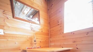 L’intérieur d’une cabane en bois, avec une table en bois, des bancs et un miroir accroché au mur.
