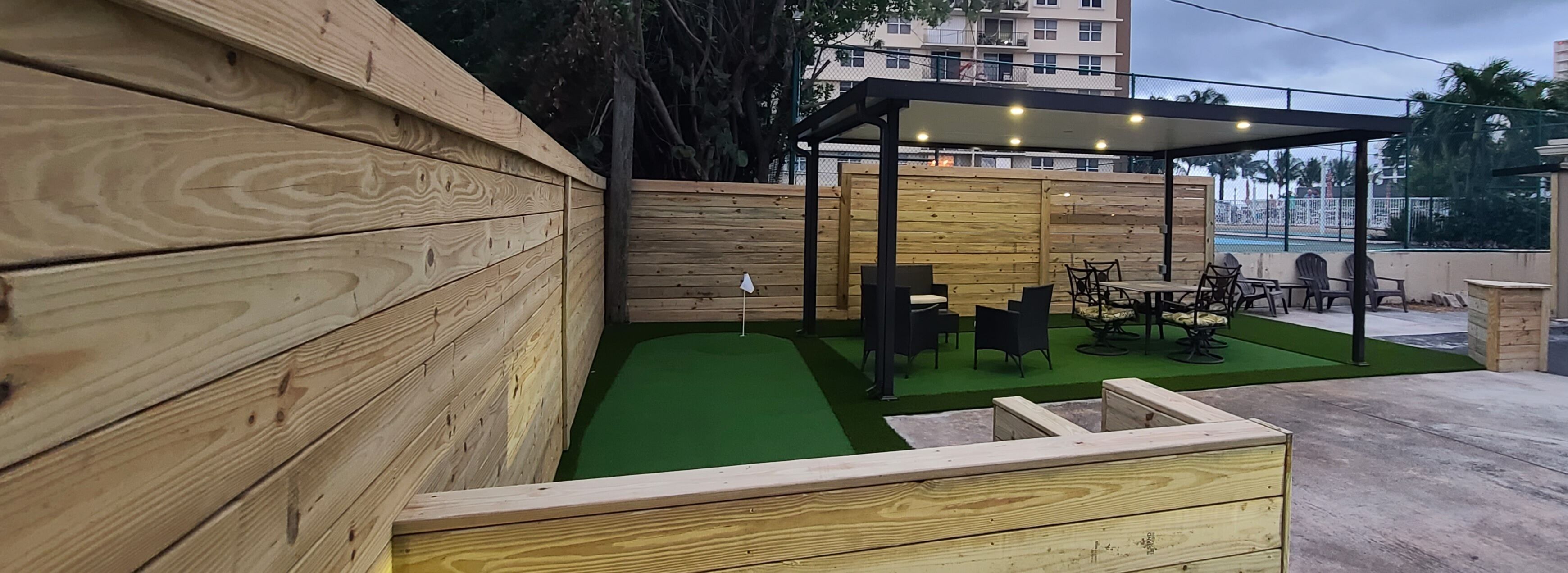 A wooden deck with a small pool, outdoor seating, and a covered area with lights.