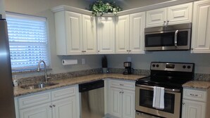 A kitchen with white cabinets, stainless steel appliances, a granite countertop, and a window with blinds. - Beach block Beauty, 500FT to the beach with chip and putt, Clean and quite.   (Pompano Beach)