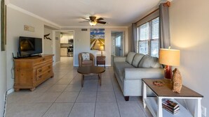 A living room with a television, sofa, coffee table, and a ceiling fan. - Beach block Beauty, 500FT to the beach with chip and putt, Clean and quite.   (Pompano Beach)