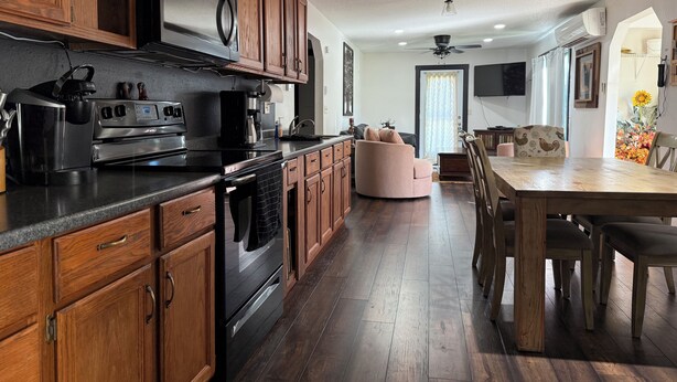 Una cocina moderna con armarios de madera, horno integrado y comedor con mesa y sillas de madera.