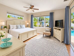 A bedroom with a bed, bedside tables, a TV, a desk, and a window with curtains.