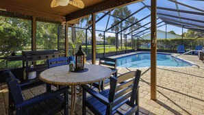 Une terrasse extérieure avec une piscine, un espace salon abrité et un coin barbecue.