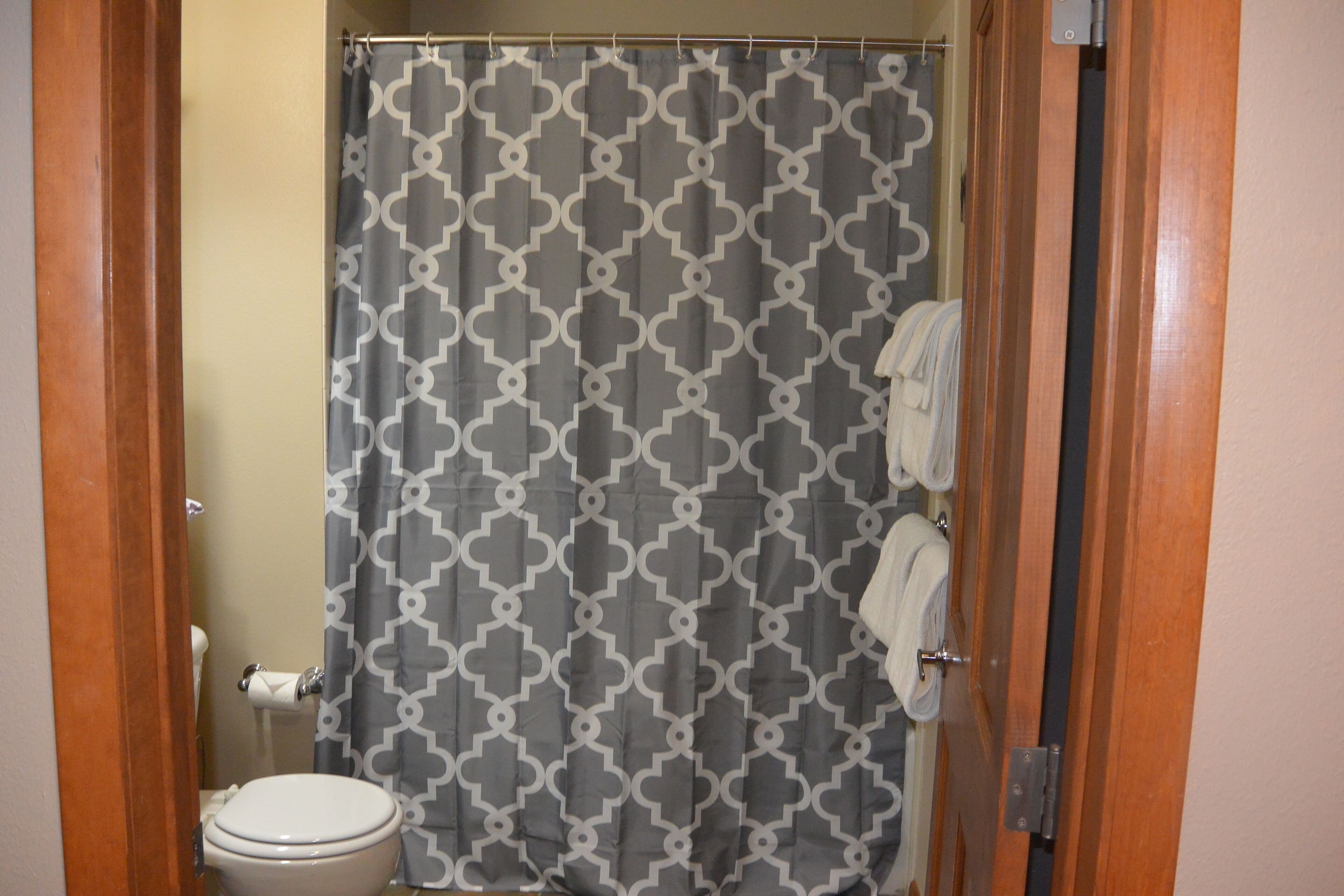 Une salle de bain équipée d’un rideau de douche, de toilettes et d’un porte-serviettes.