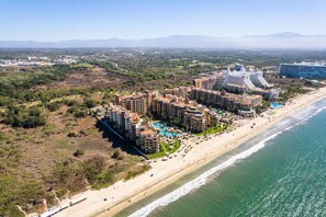 Un complejo turístico costero con varios edificios de gran altura, una playa y una amplia piscina.
