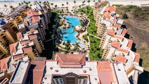 Um resort com vários edifícios, uma piscina central e uma praia.