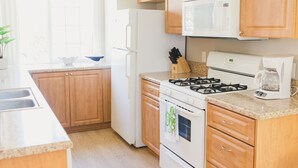 A kitchen with wooden cabinets, a white refrigerator, a stove, and a microwave. - Beachy and Clean!  White Water Views! (Oceanside)