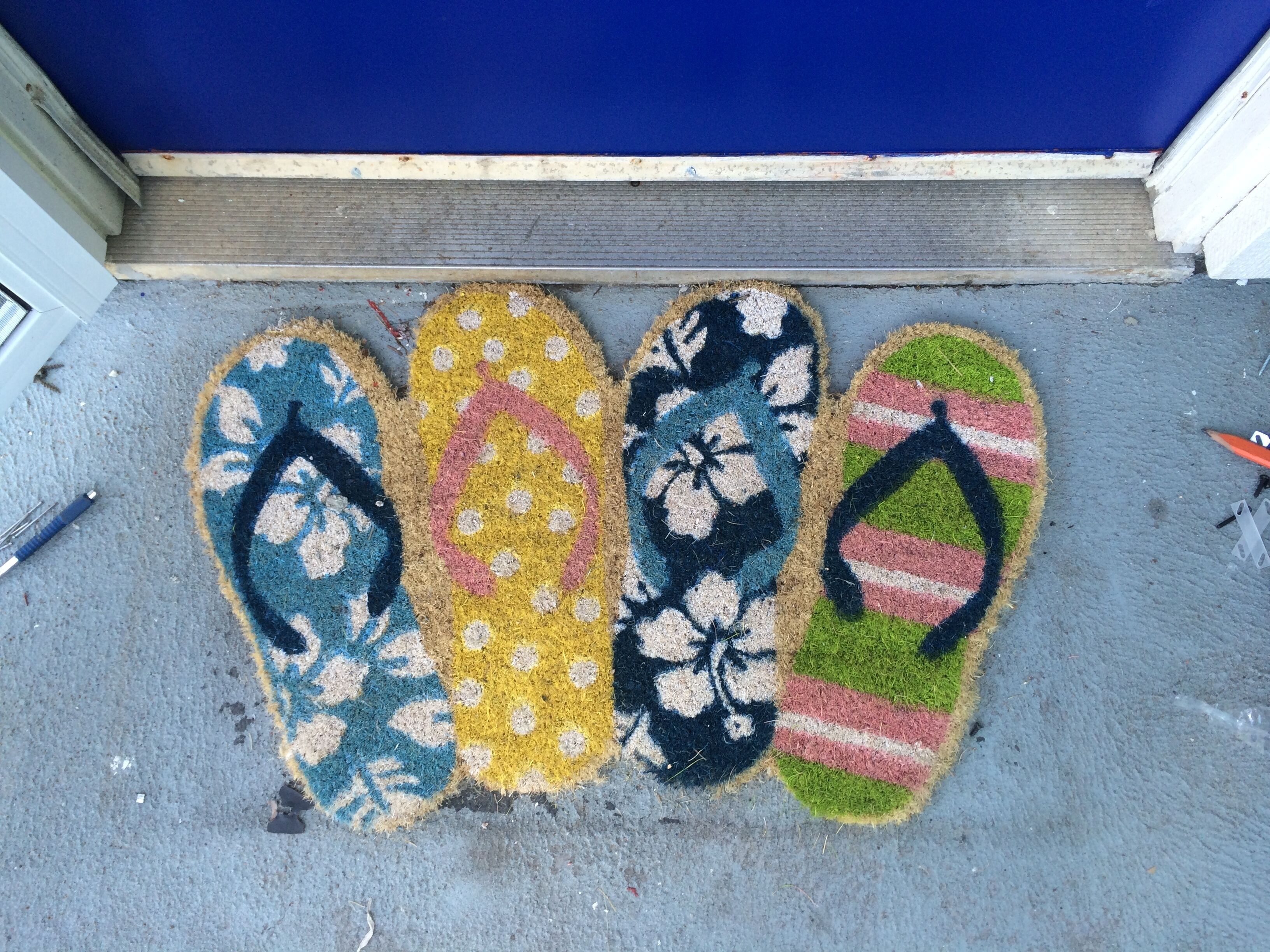 A set of colorful, patterned mats on a grey surface, likely a doormat.