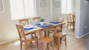 A dining area with a wooden table set for six, surrounded by wooden chairs. - Beachy and Clean!  White Water Views! (Oceanside)