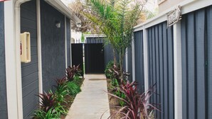 A narrow pathway flanked by dark blue fences and various plants. - Beachy and Clean!  White Water Views! (Oceanside)