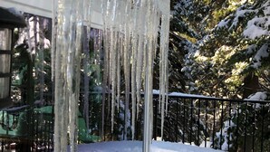 Icicles hanging from a window sill, a snow-covered deck, and a view of snow-laden trees. - Historic Hershey Cabin, Most 10 Star Reviews, Romantic, Just for 2, Immaculate (Lake Arrowhead)