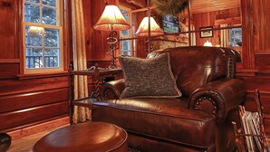A cozy room with a leather armchair, a wooden table, and a lamp. - Historic Hershey Cabin, Most 10 Star Reviews, Romantic, Just for 2, Immaculate (Lake Arrowhead)