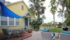 A patio with outdoor furniture, a blue awning, and a yellow building with a window and door. - Steps2Beach-Walk everywhere-Bikes & gear Included (St Pete BEach)