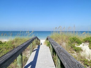 A wooden boardwalk leading to a beach with clear blue water and sandy dunes. - Steps2Beach-Walk everywhere-Bikes & gear Included (St Pete BEach)