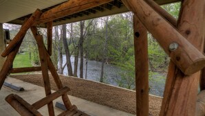 A wooden swing set overlooking a river with trees and a grassy area in the background. - Amy's Waterfront Blessing w/ Hot Tub, Arcade , & Fishing 2 King Master Suites (Pigeon Forge)