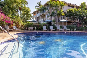 A swimming pool with lounge chairs and umbrellas, surrounded by palm trees and a multi-story building. - 5 Star Ocean View, Beach House Chic, Click the Video tour below! (Wailea)
