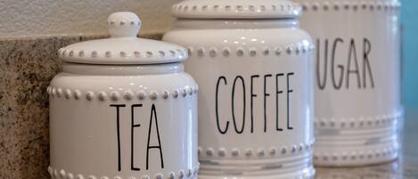 Three white ceramic containers with labels for tea, coffee, and sugar.