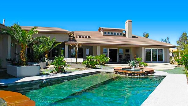 A modern house with a swimming pool, a patio area, and a well-maintained garden.