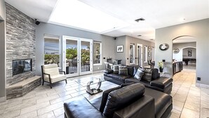 A spacious living room with a stone fireplace, a large sofa set, and a dining area with a pool table.