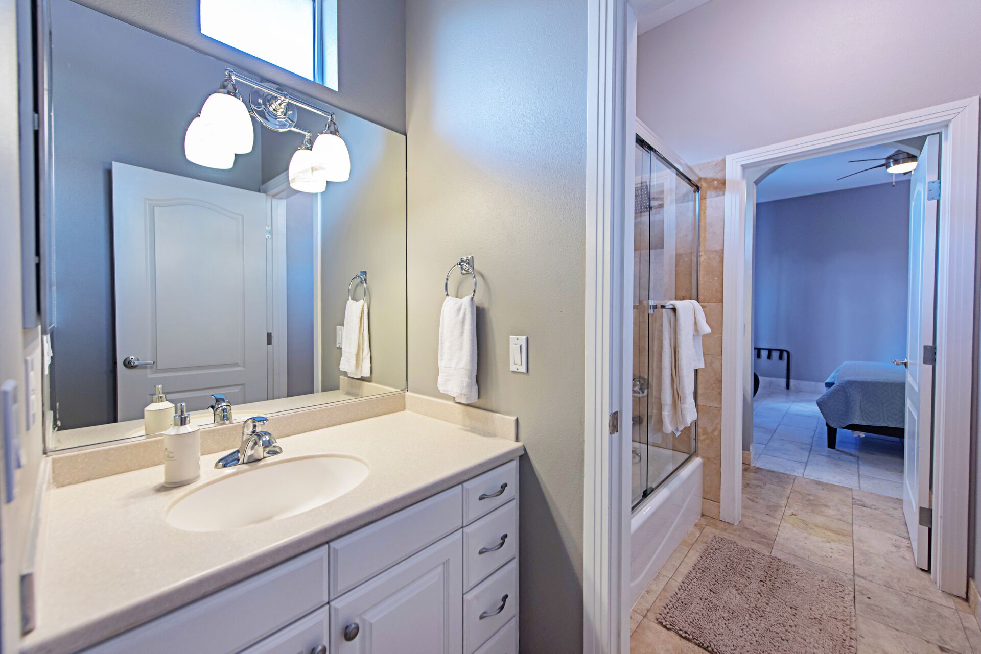 Une salle de bain moderne avec un grand miroir, un lavabo et un espace douche.