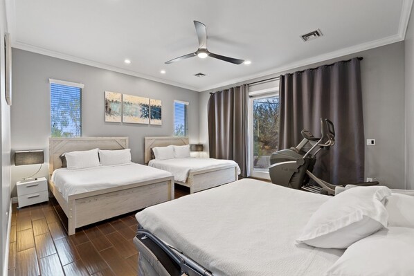 Une chambre d’hôtel moderne équipée de deux lits, d’un ventilateur de plafond et d’un tapis de course.