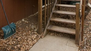 A wooden staircase leading to a front door with a red door and a green wreath. - The 8th Street Retreat Looks Booked it may not be Call Us (Carbondale)